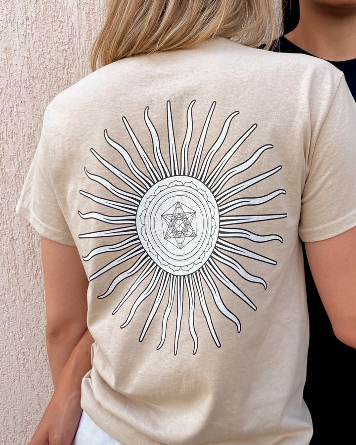 En person set bagfra i en sandfarvet t-shirt med Metatrons terning sol.
